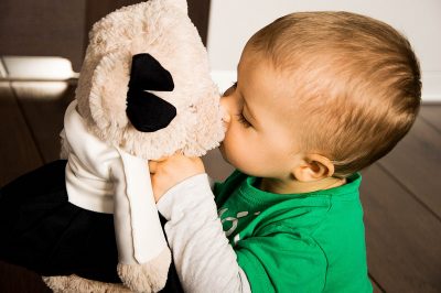 A young boy kissing his stuffed animal toy