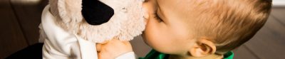 A young boy kissing his stuffed animal toy