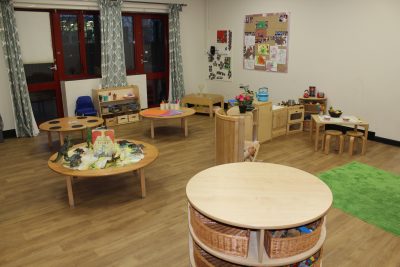 A child's playroom with wooden tables and chairs