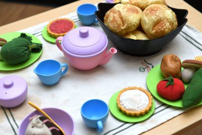 A table topped with toy plates and bowls filled with toy food