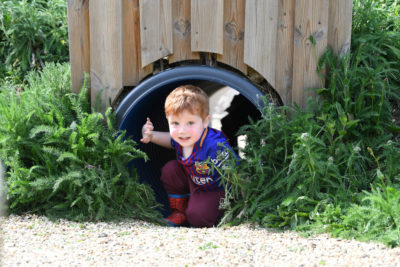 A little boy that is looking out of a tunnel