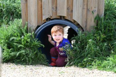 A little boy that is looking out of a tunnel
