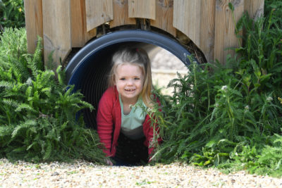 A little girl that is looking out of a tunnel