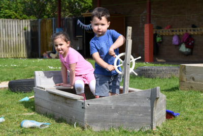 2 children playing on an outdoor wooden pirate ship