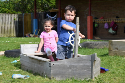 2 children playing on an outdoor wooden pirate ship