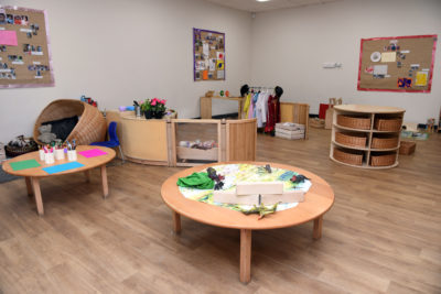A playroom filled with wooden tables and chairs