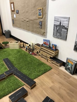A room with a toy car and a green carpet